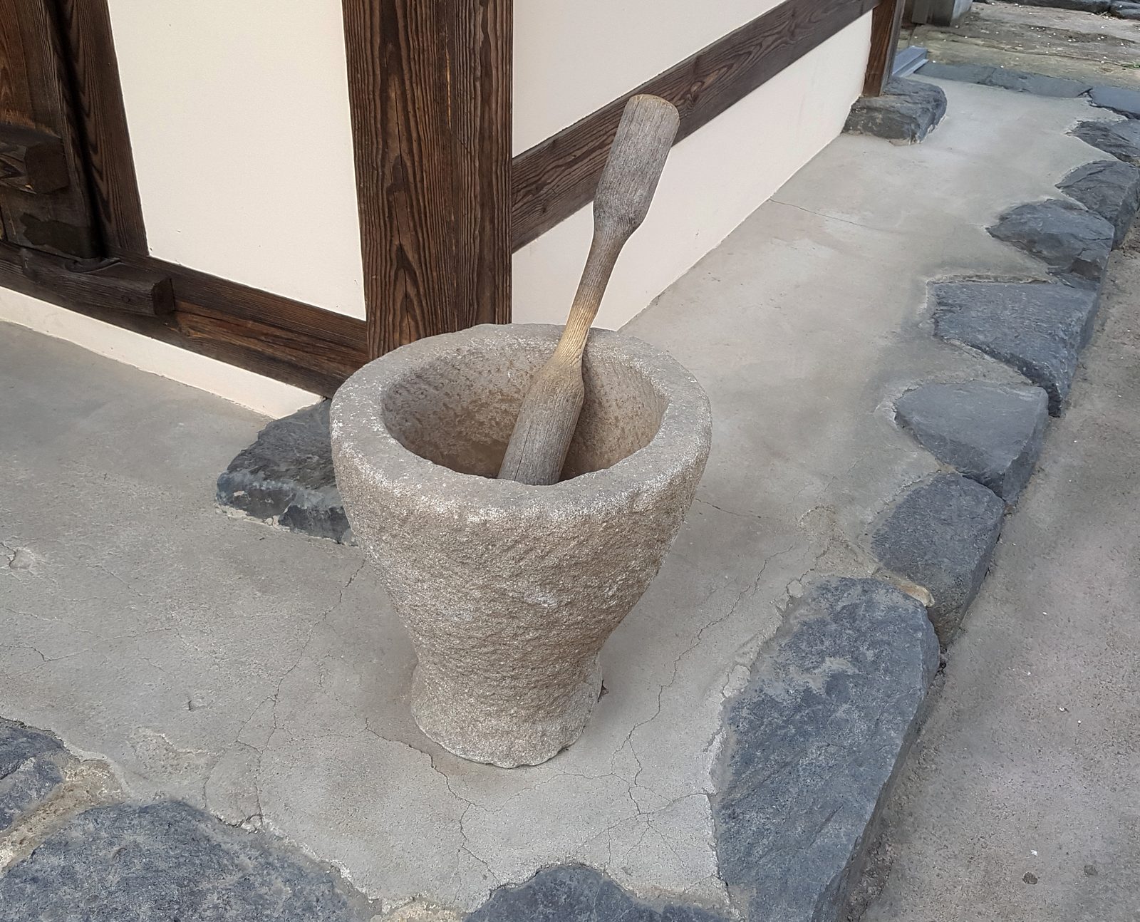 마당에 놓인 돌 그릇이에요. 위가 넓고 아래로 갈수록 좁아져요. 그릇 안에 굵은 나무 방망이가 꽂혀 있어요.