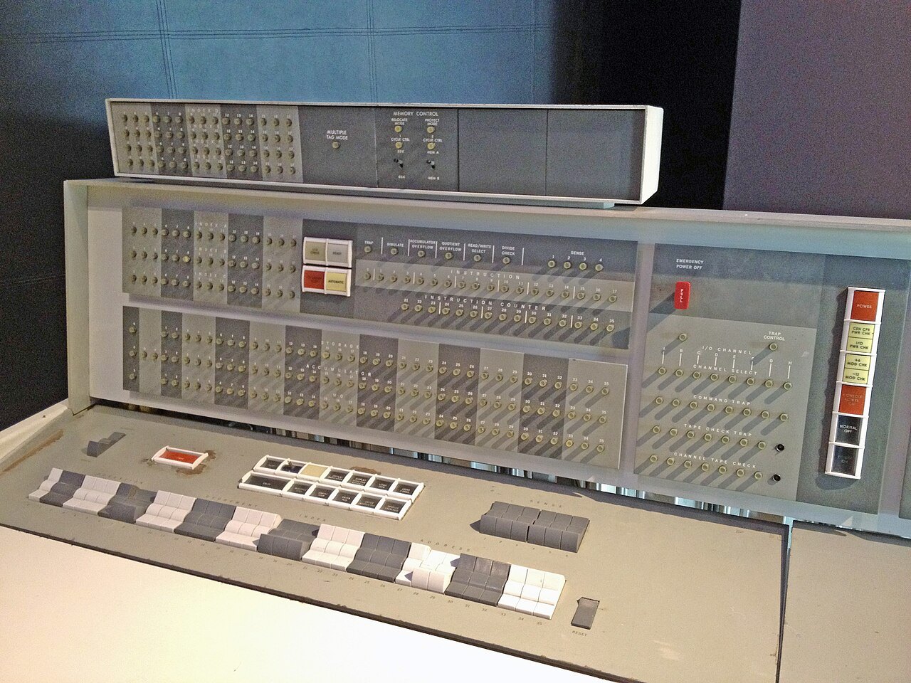 박물관에 전시된 IBM 7094 컴퓨터의 조작반. 회색 패널에 작은 표시등이 줄지어 박혀 있고, 앞쪽 책상면에 흰색·회색 누름단추가 늘어서 있다