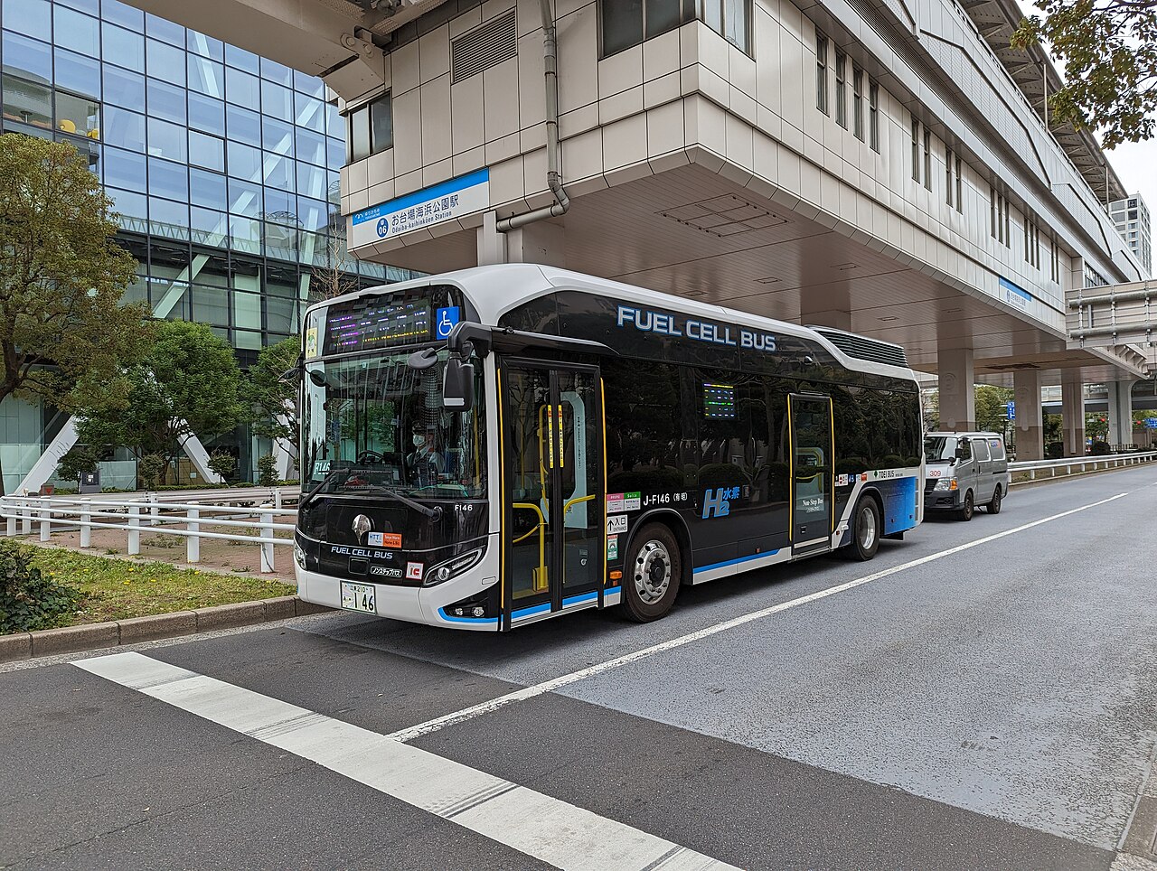 차체에 'FUEL CELL BUS'와 'H2'가 적힌 검은색 대형 버스가 도심 역 앞 도로에 서 있다.